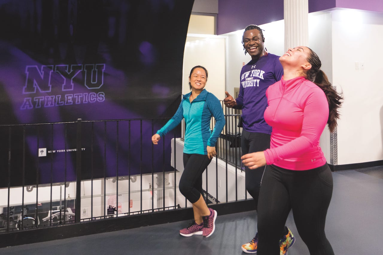 Three students have fun walking together through NYU's fitness facility.