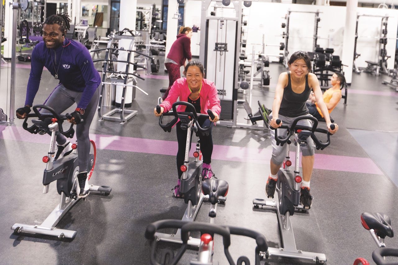 Three students use stationary exercise bicycles.