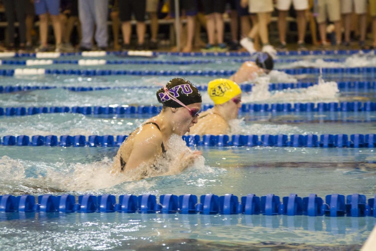 Honore Collins swims in a race against other collegiate competitors.