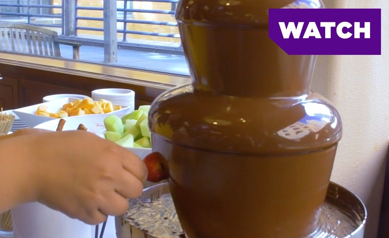 A student dips a strawberry into a chocolate fountain at an NYU dining hall