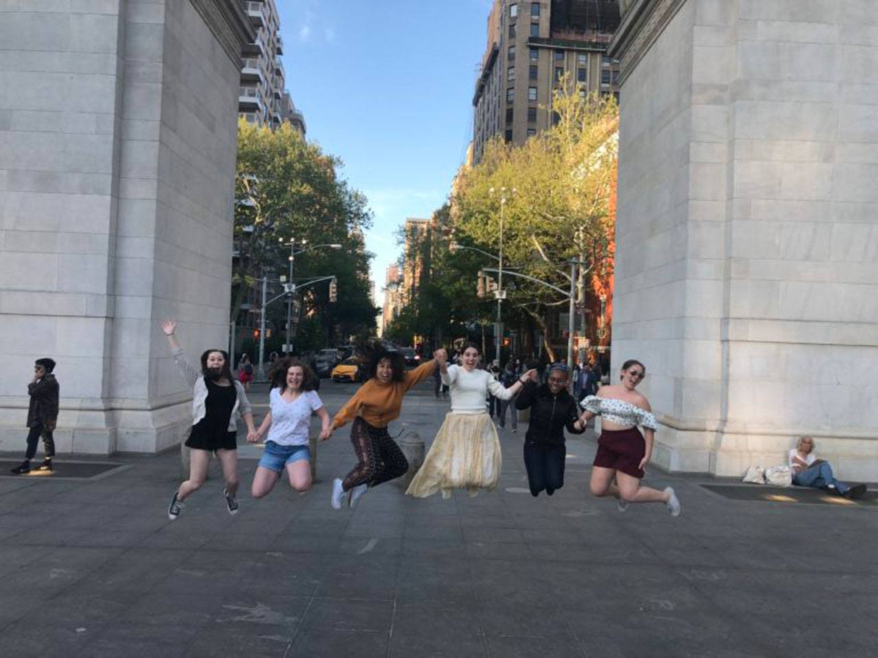 Students jumping near Washington Square Arch