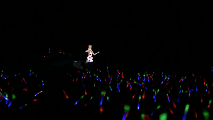 Host of ultraviolet live, Alaska waves a glow stick along with the audience.