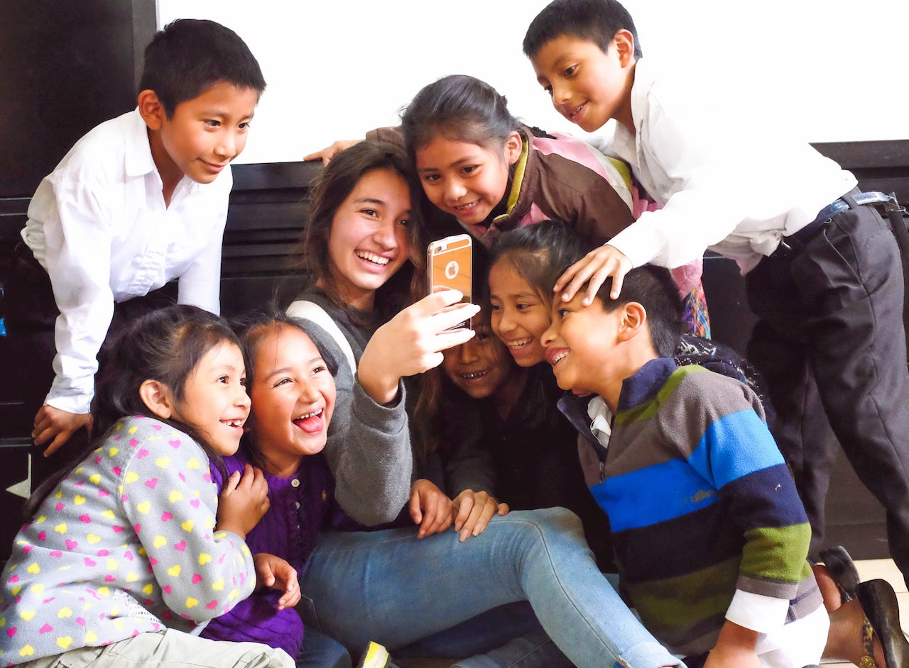 A female student shows her iPhone to eight children.