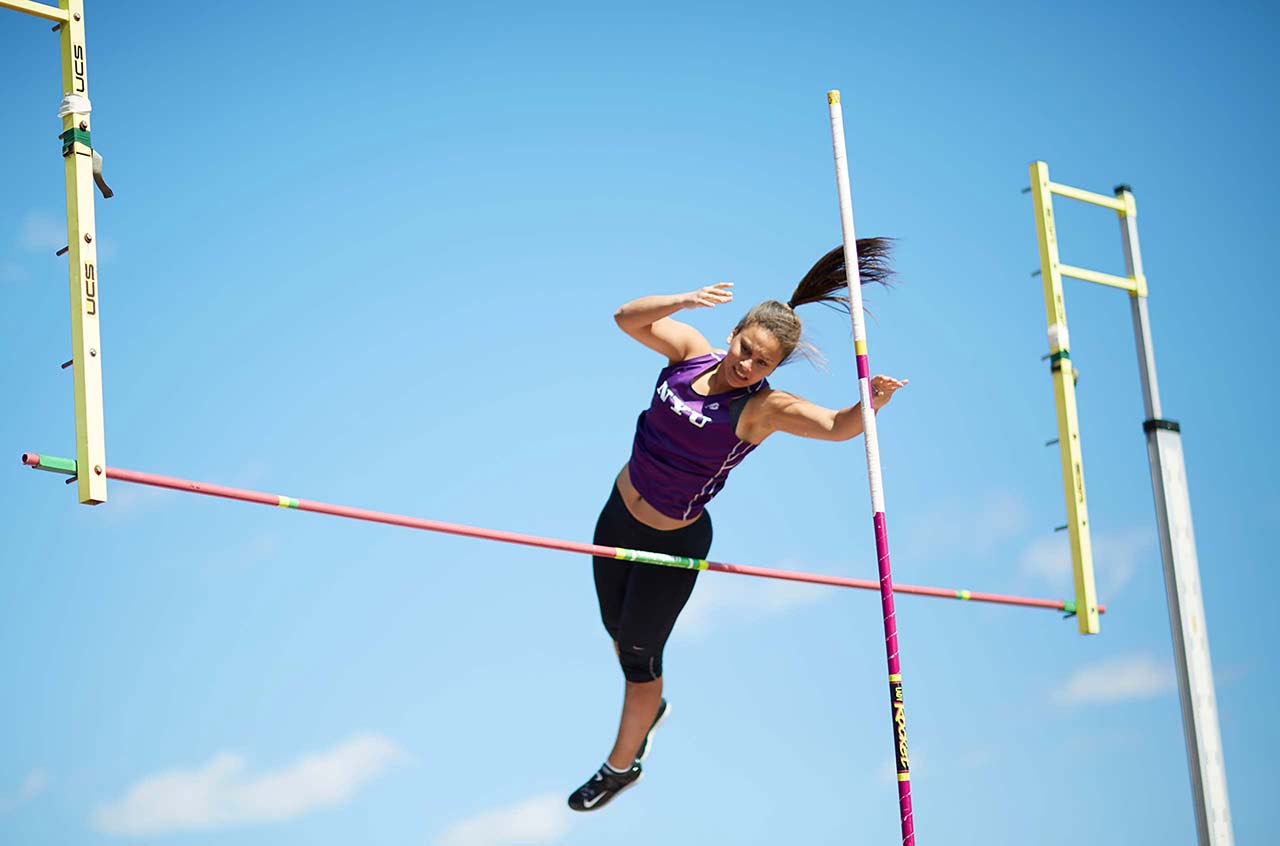 female track and field athletic in midair clearing a high jump