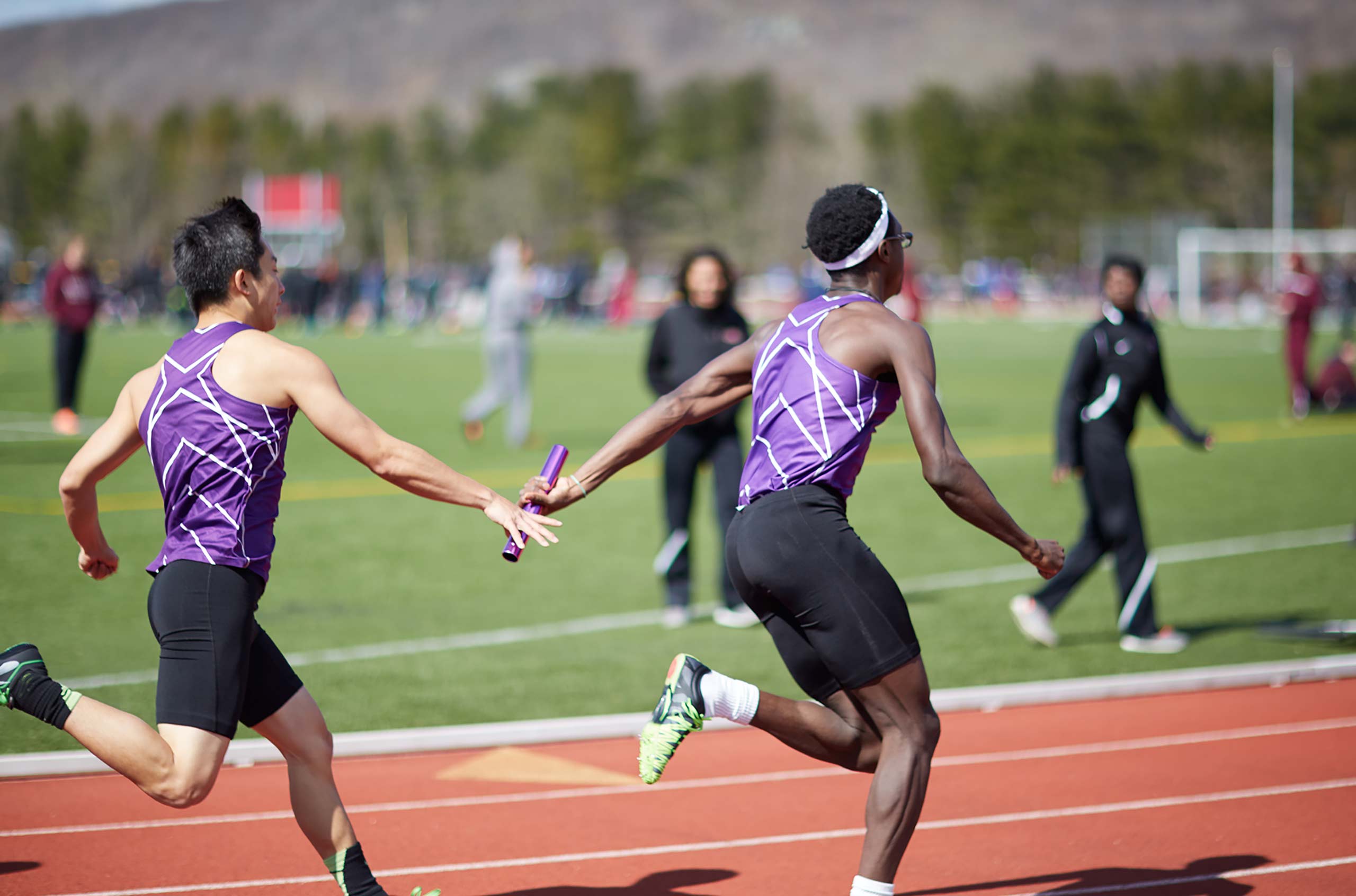 NYU track team passes baton during relay race