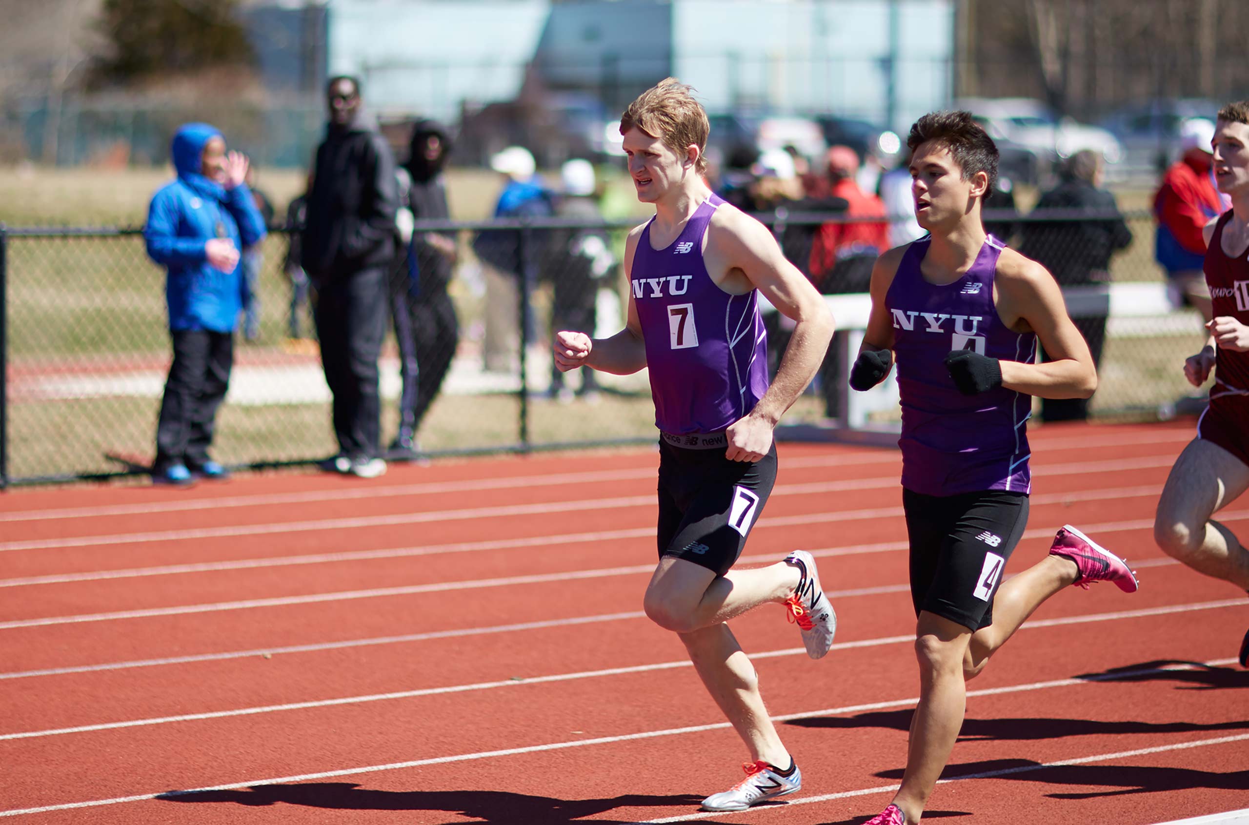 Two NYU track team members participating in a race