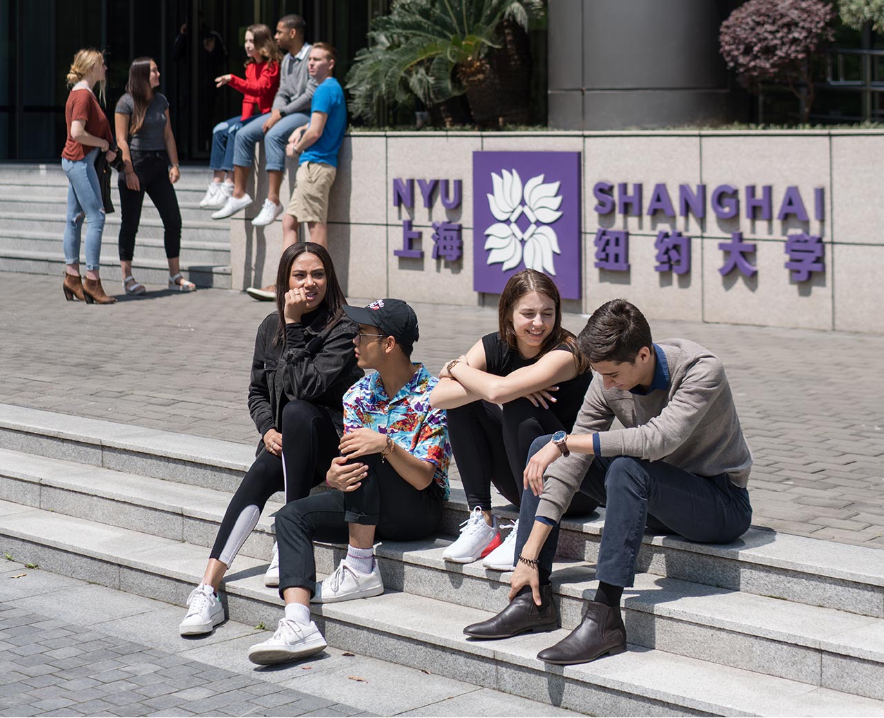 A group of students sitting outside NYU Shanghai.