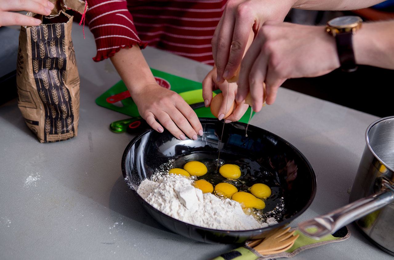 cracking eggs into a pan of flour to make crepes