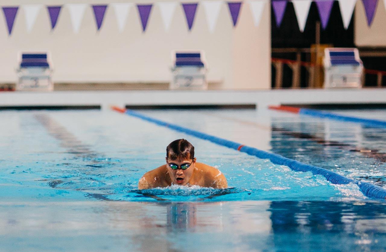 An NYU swimmer coming up for air in a lap lane.