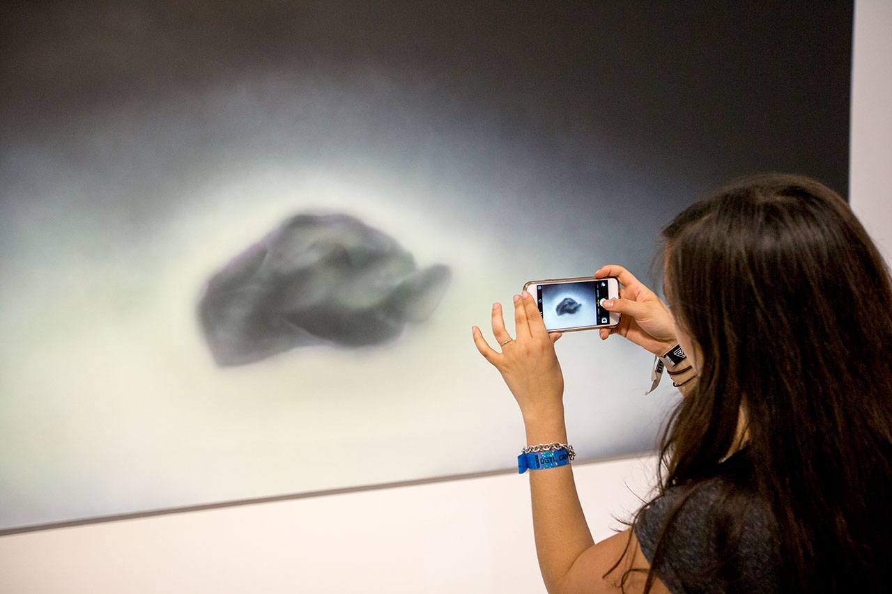 A student takes a photo of a piece of art