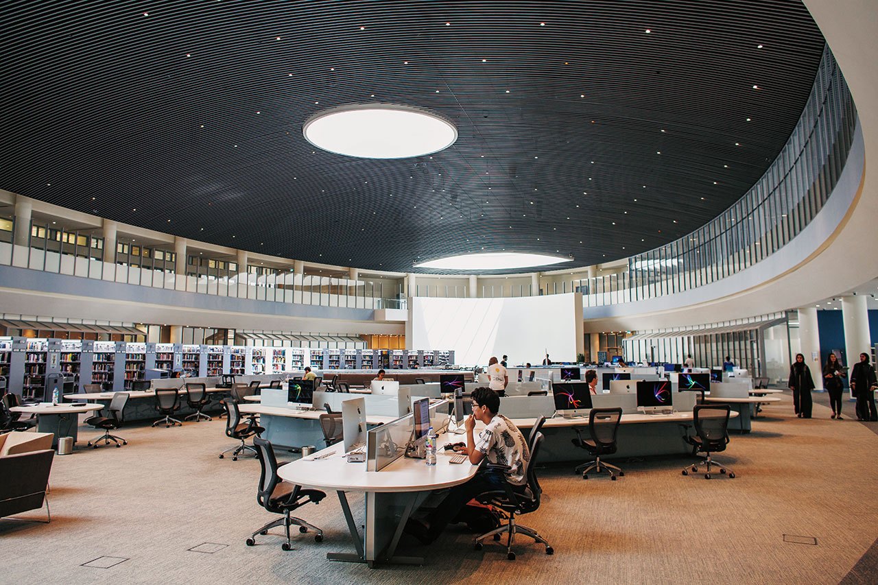 Students working within the open space of the NYU Abu Dhabi library.