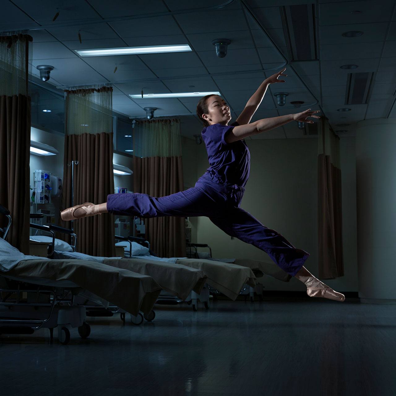 Nursing student Brittney Tam leaping in the air in a hospital room.