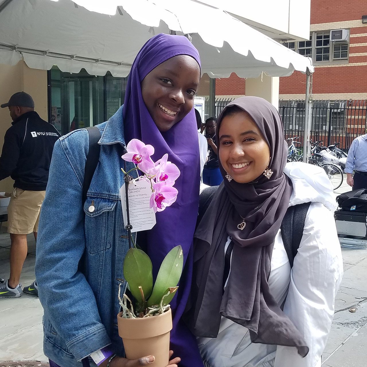 Two female students on Move-In Day. One is holding a plant.