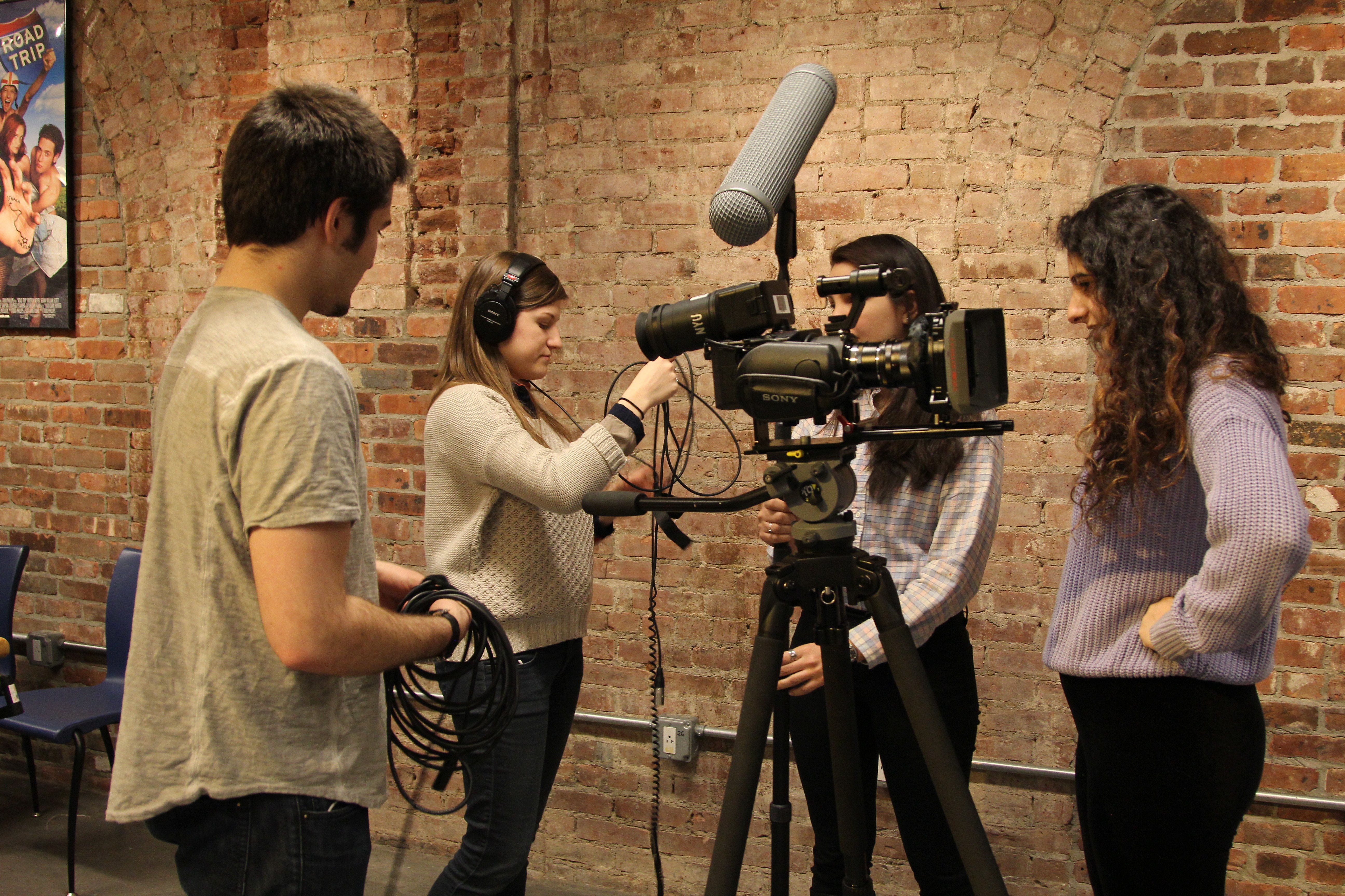 Students huddle around a film camera.