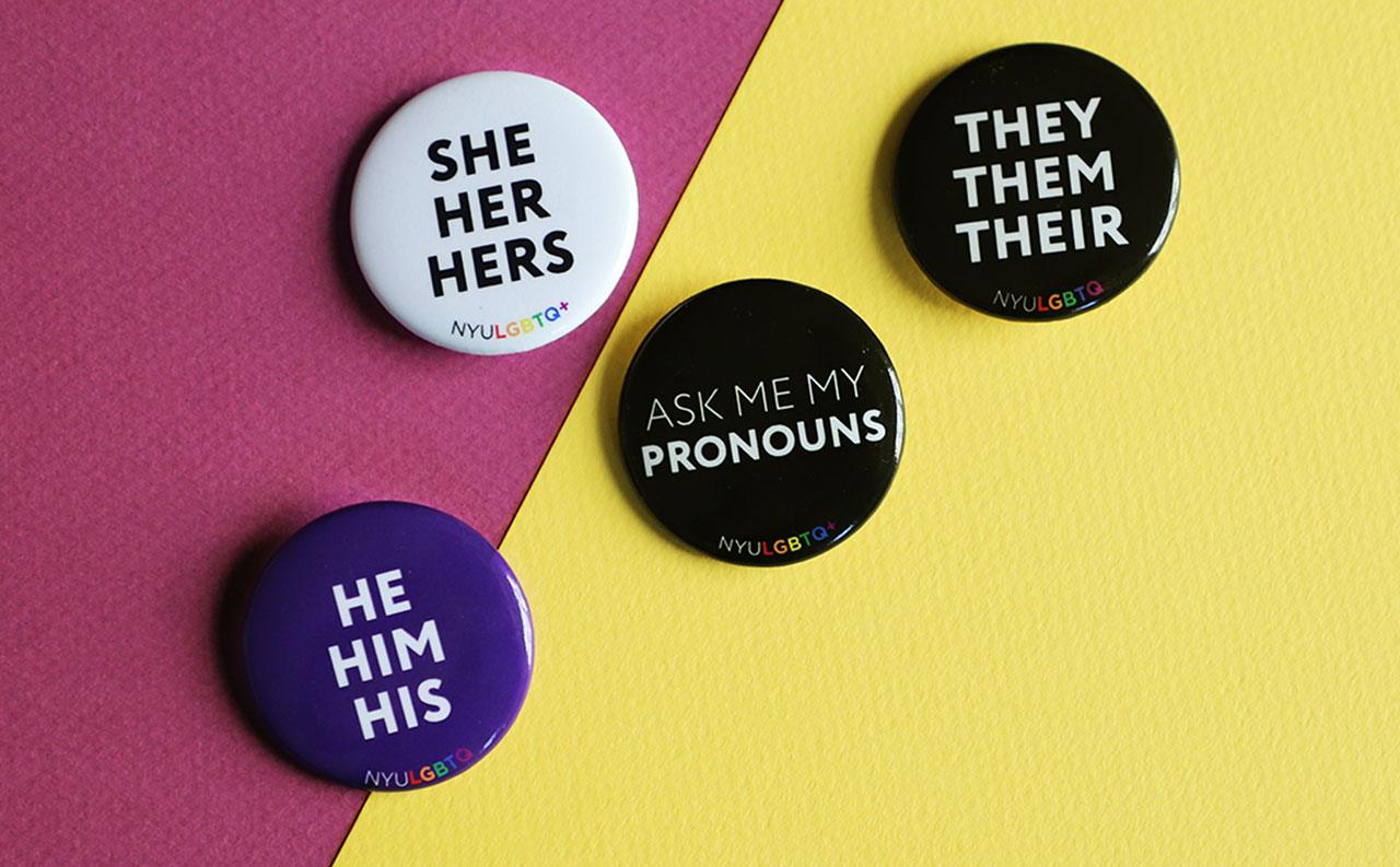Four pronoun pins sitting on colored sheets of paper.