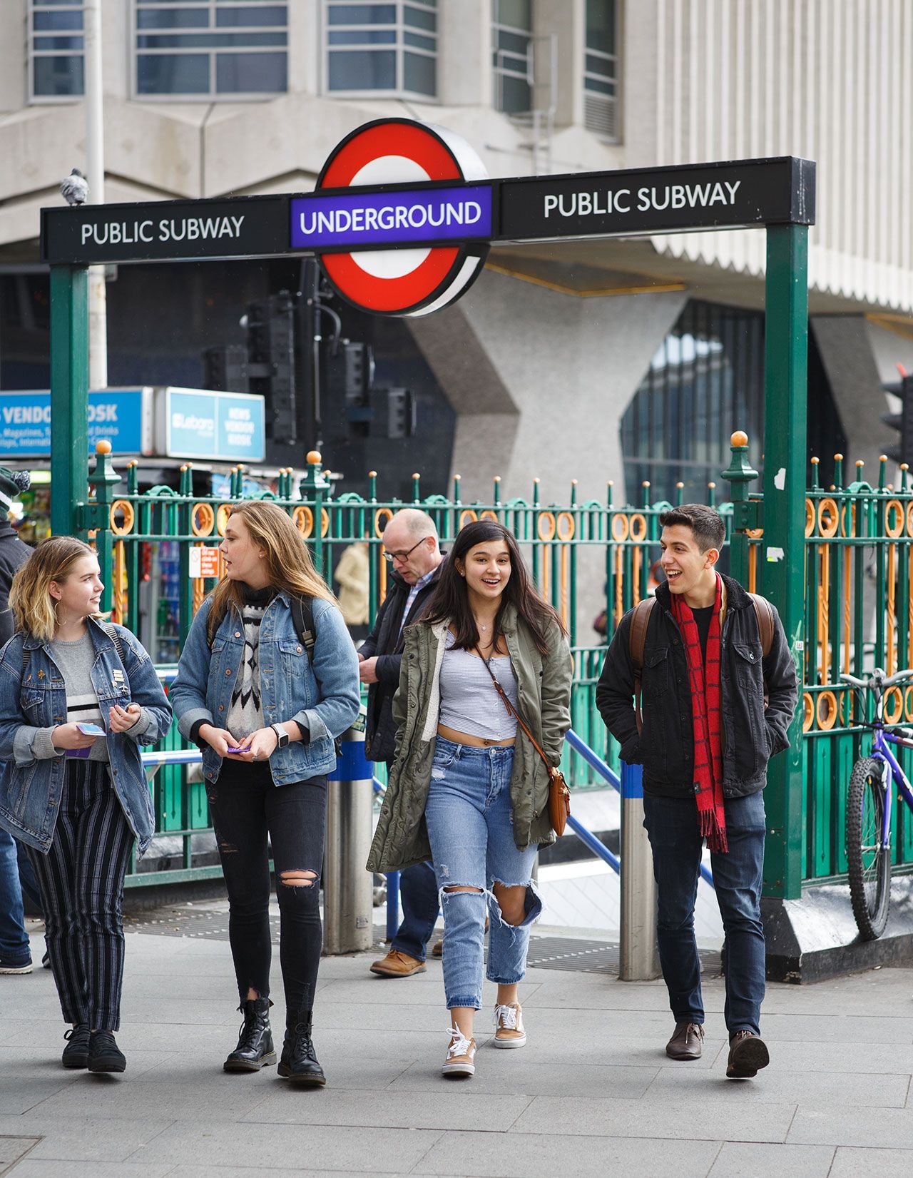 A group of students walking in front of a London subway station.