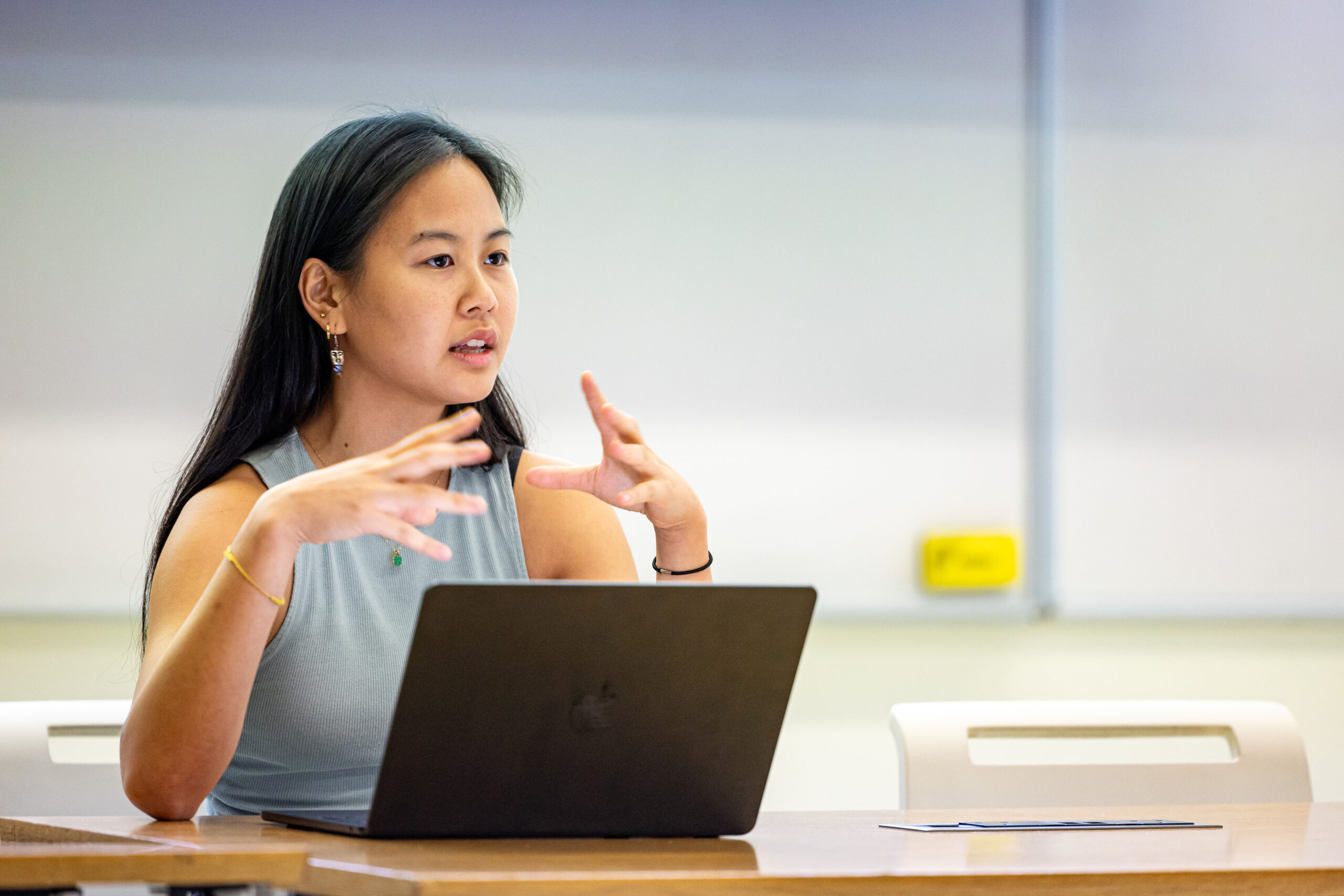 A student speaking in class with their laptop in front of them.