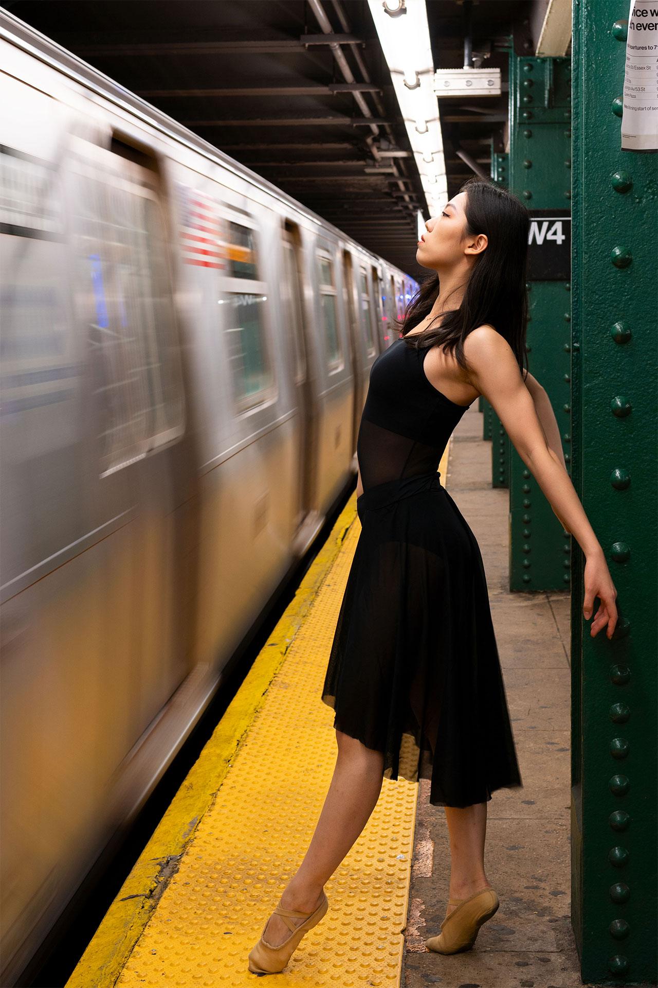 Dancer posing while subway car speeds past her.