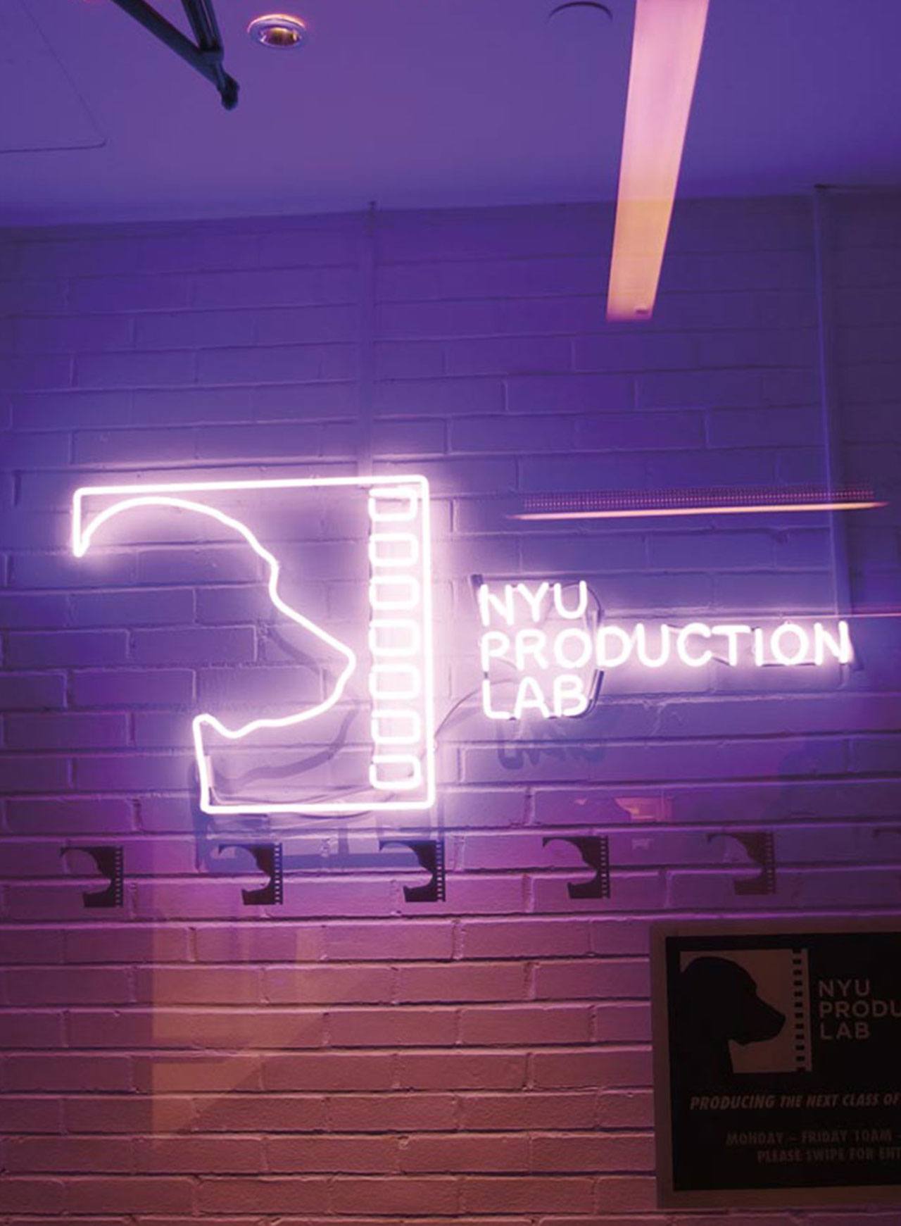 A sign made from glowing pink lights that says, “NYU Production Lab.”