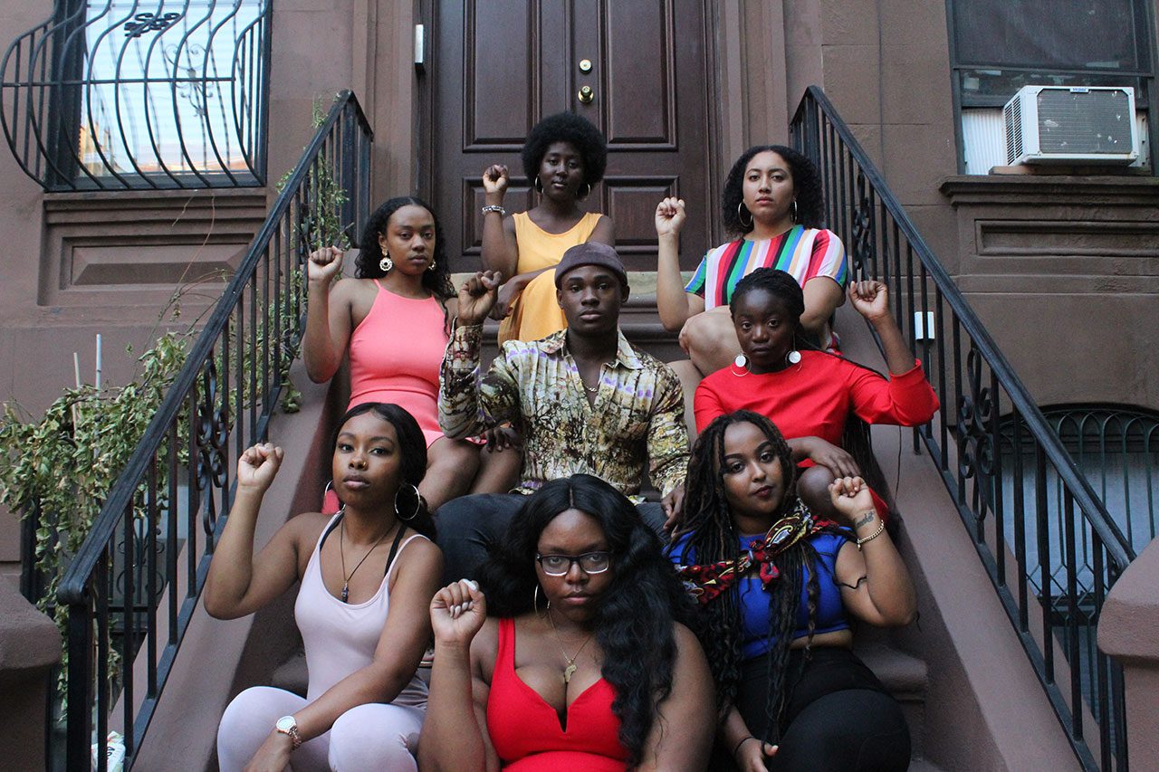 Black Student Union members sit on the front steps of a brownstone.