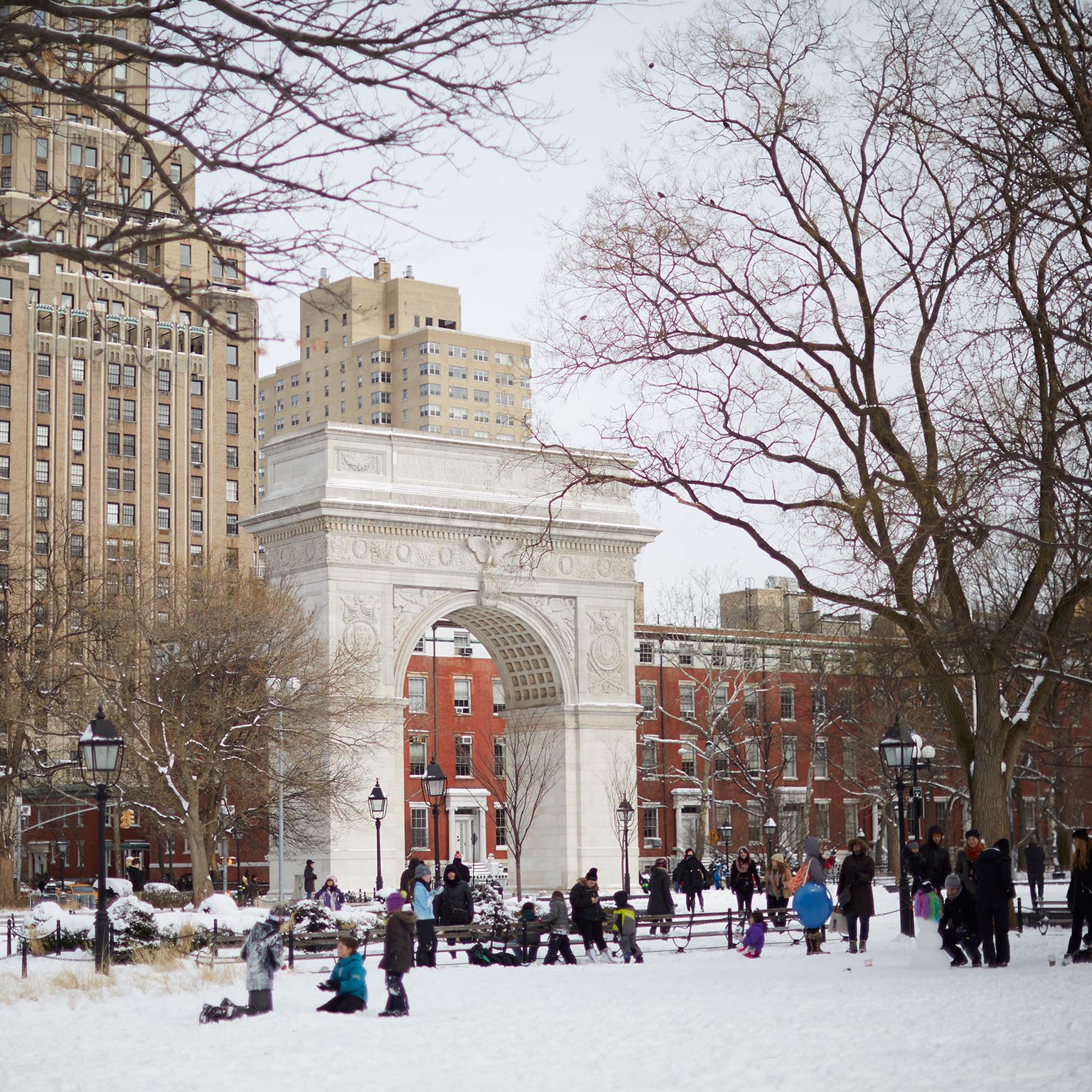 Families enjoy the snow in Washington Square Park during winter recess.