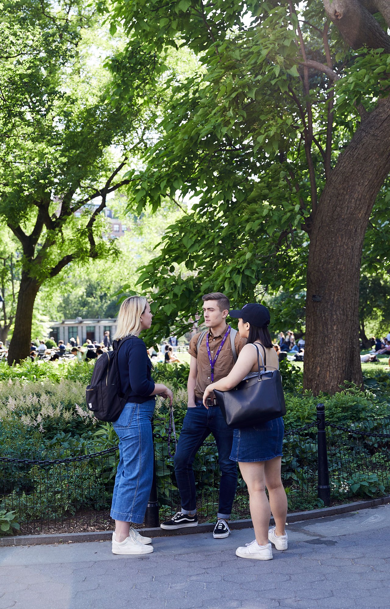 Students standing in a circle and talking in Washington Square Park.