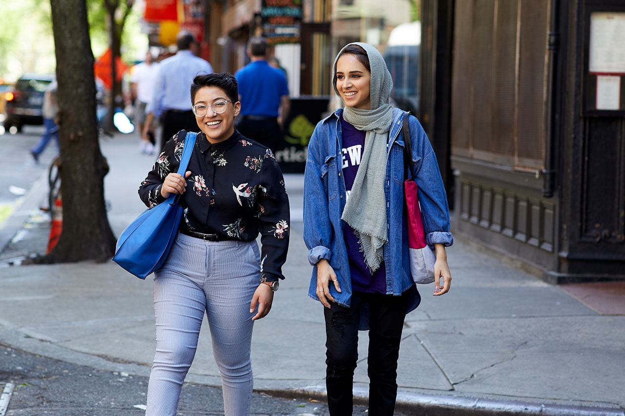 Two students talking and crossing a street in New York City.