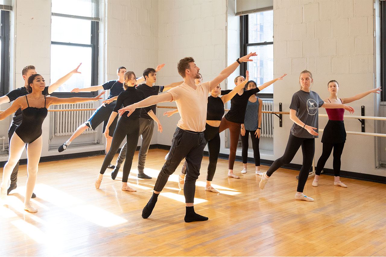 A ballet class with a group of students following the professor’s instruction at the front.