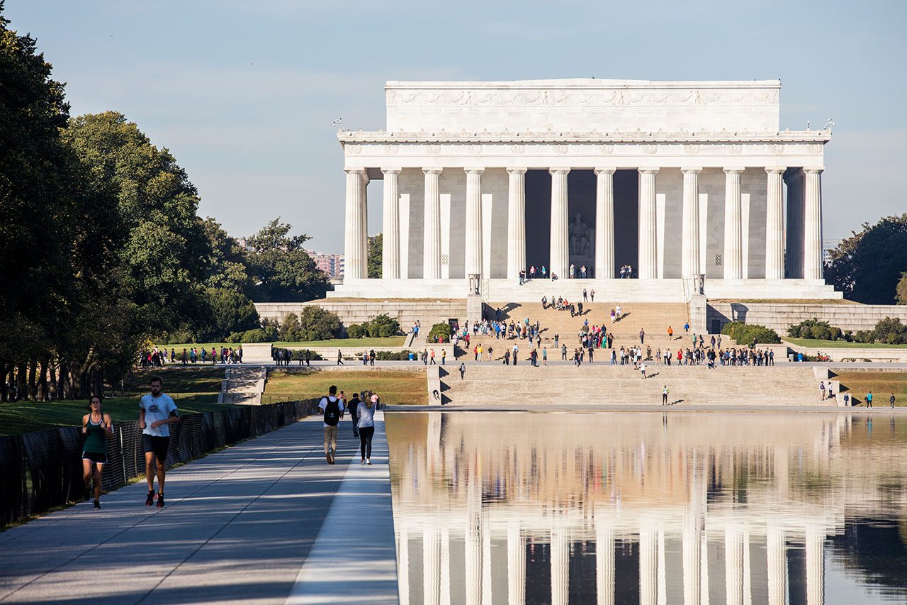 People walking around the Lincoln Memorial Reflecting Pool and siting on the memorial’s steps.