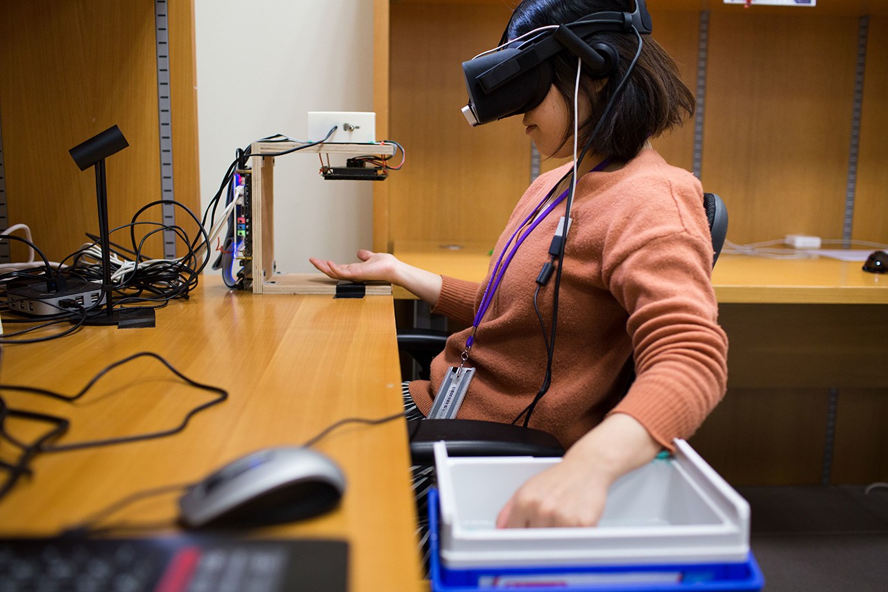 A student wearing virtual reality goggles while working on a project.