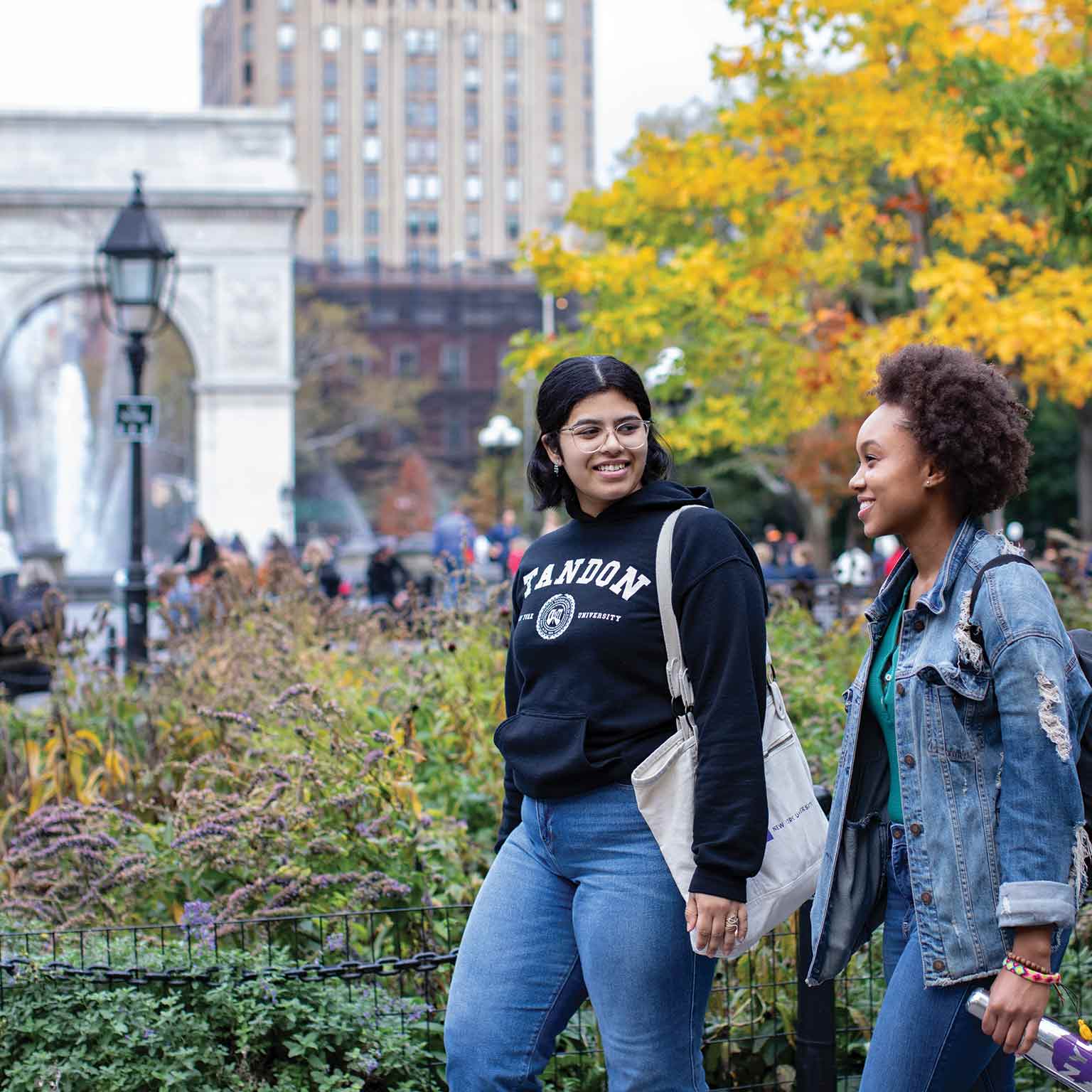 Two students walking in Washington Square Park.