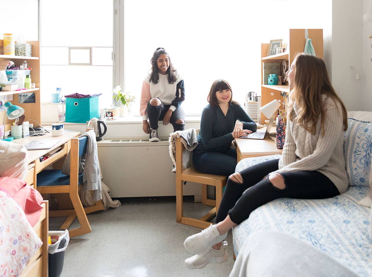 Three students hanging out in an NYU dorm room.