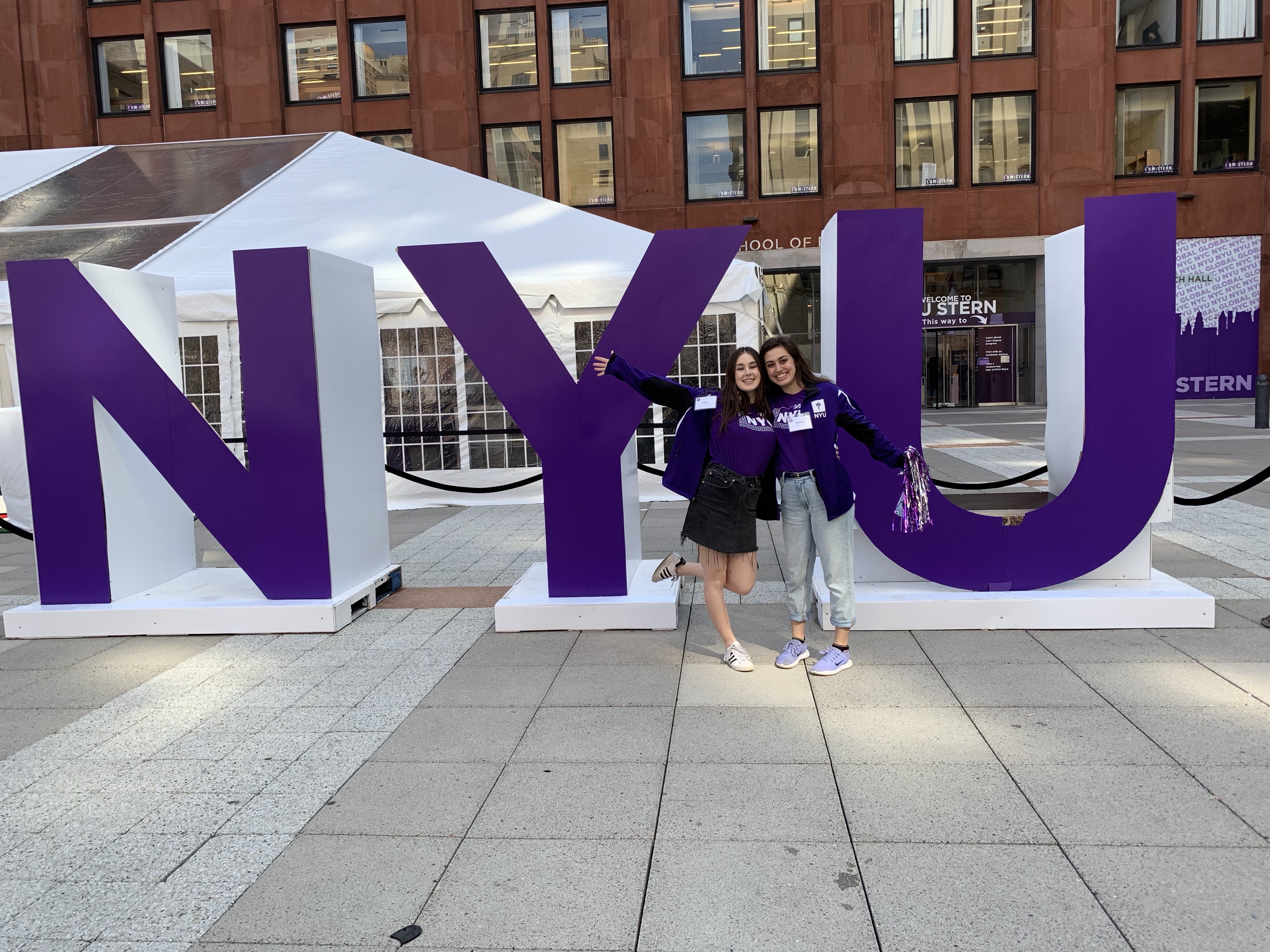 Two NYU Students in front of the NYU letters
