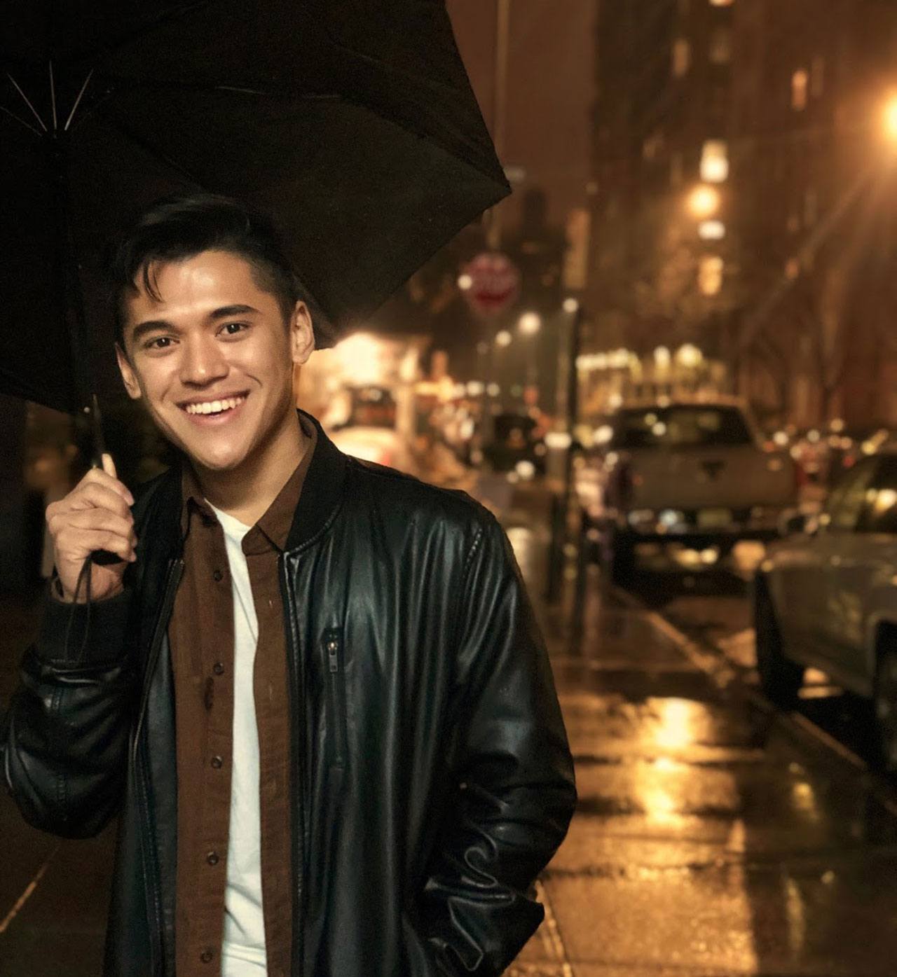 CAS student Justin Gimoto posing while holding an umbrella.