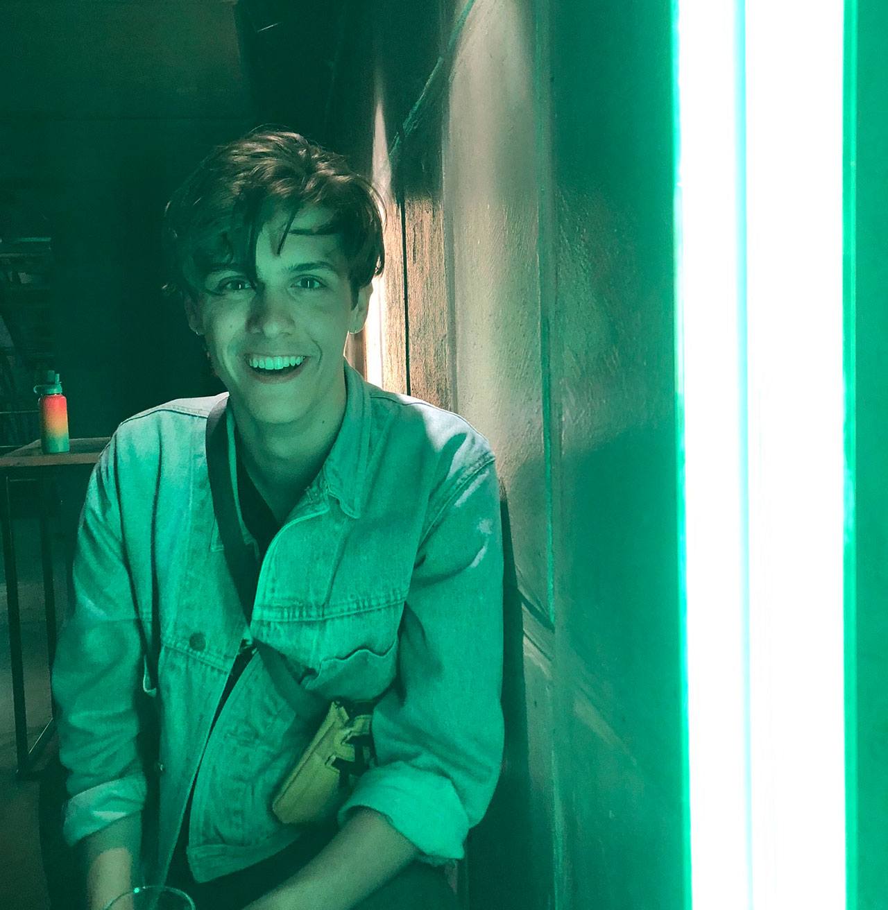 Justin Kipp posing in front of a vibrant green neon light.