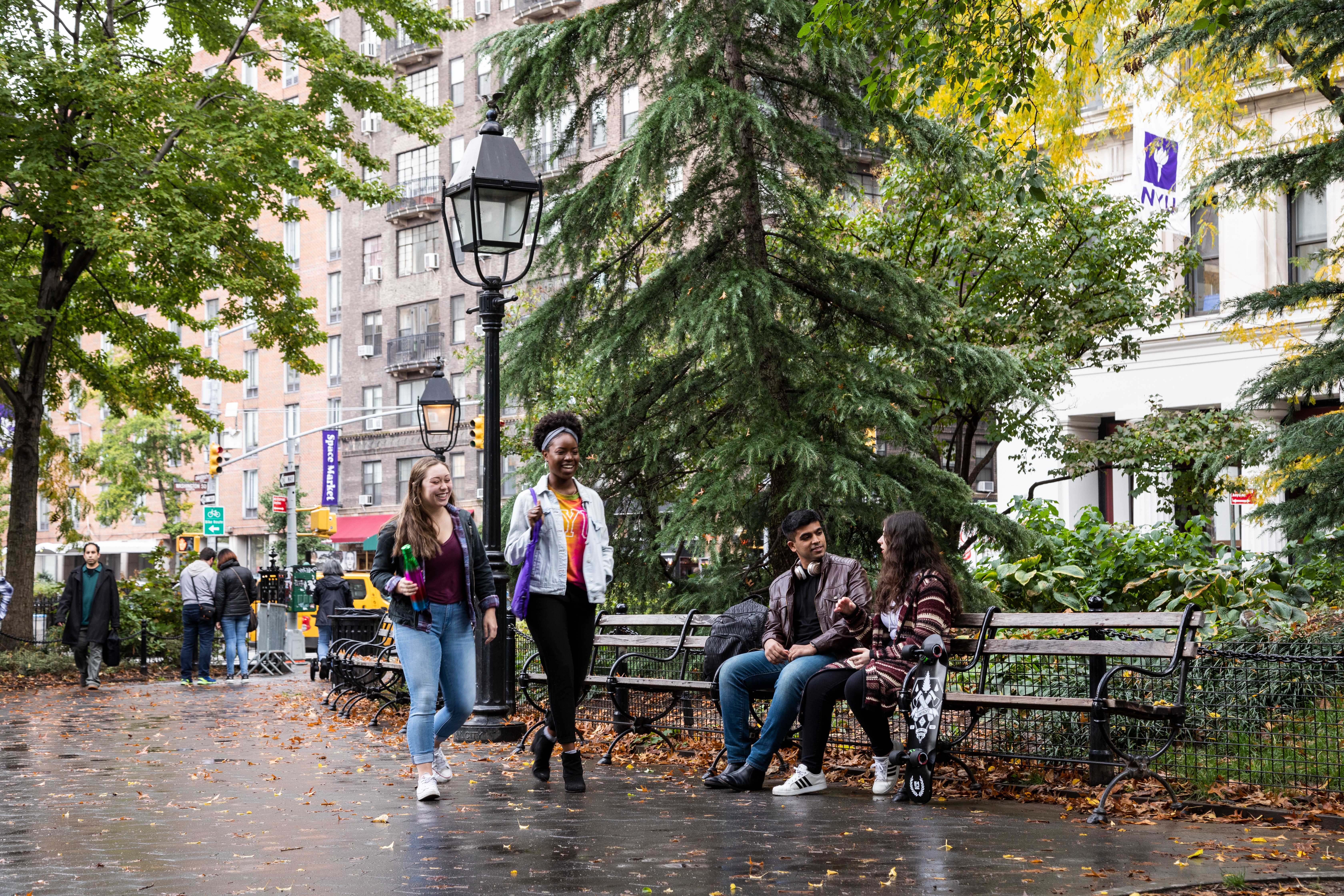 Students walking and sitting in Washington Square Park.