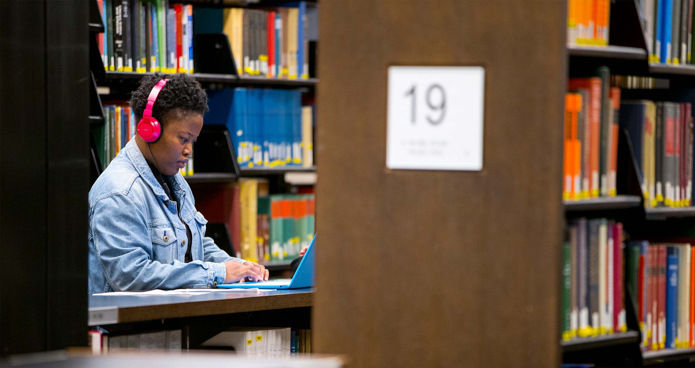 A student sits at a desk studying with headphones on