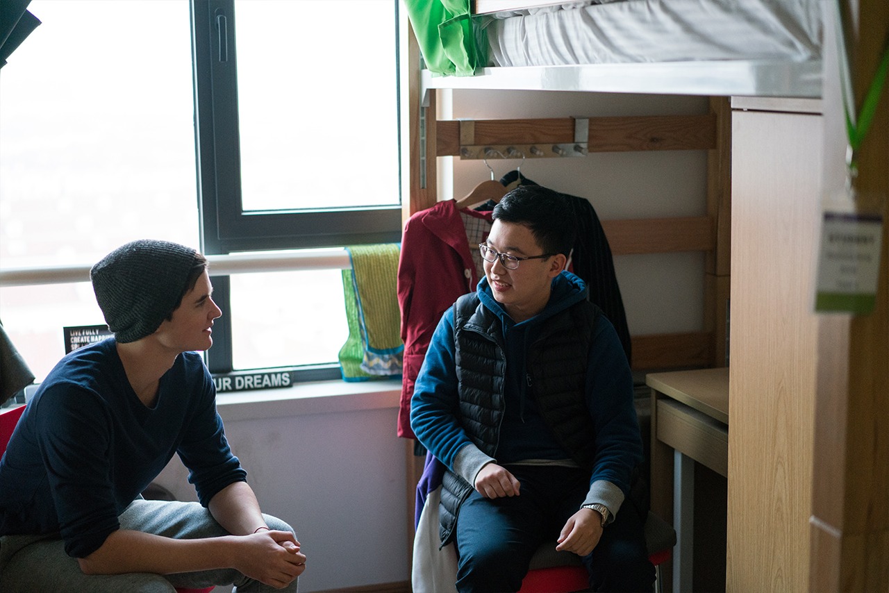 Two students hanging out in a dorm room.