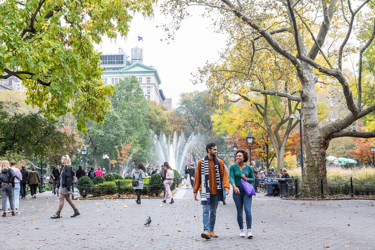 Students walking through Washington Square Park in the fall.