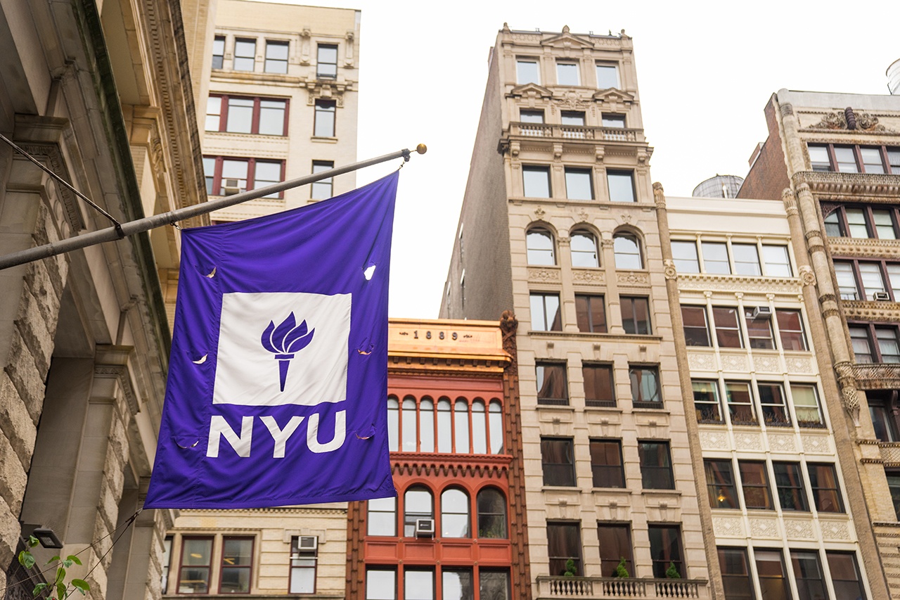 An NYU flag hanging from a building.