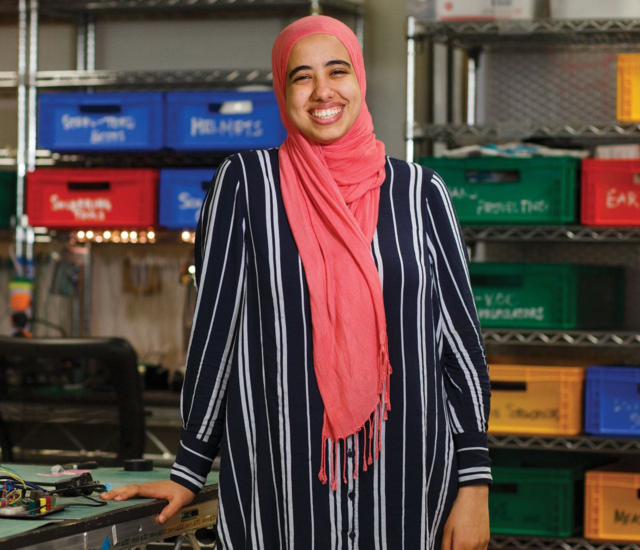 Portrait of Computer Science major Alia ElKattan. There are various tech parts behind her.