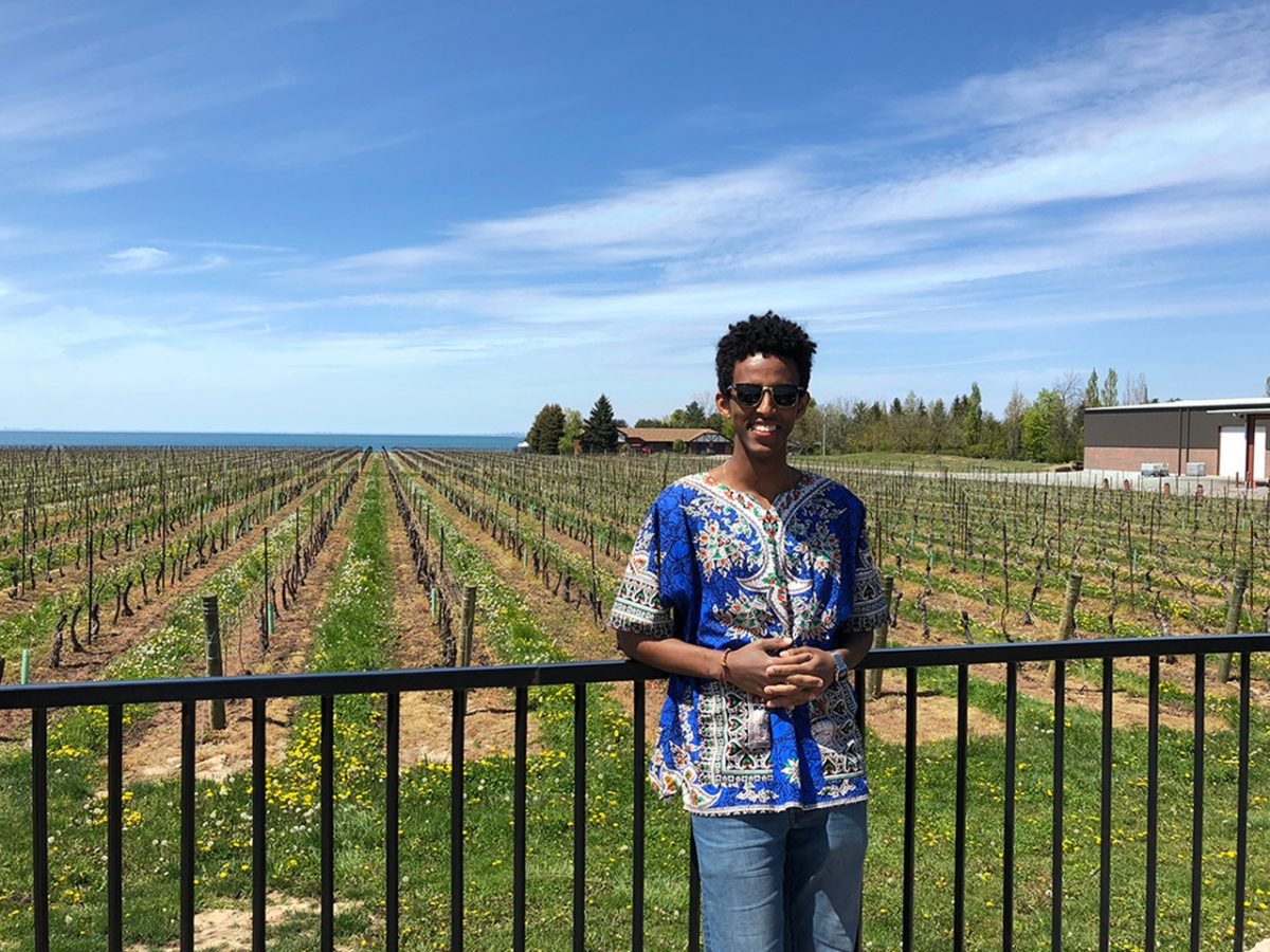 Beamlak Hailemariam posing in front of crop rows.
