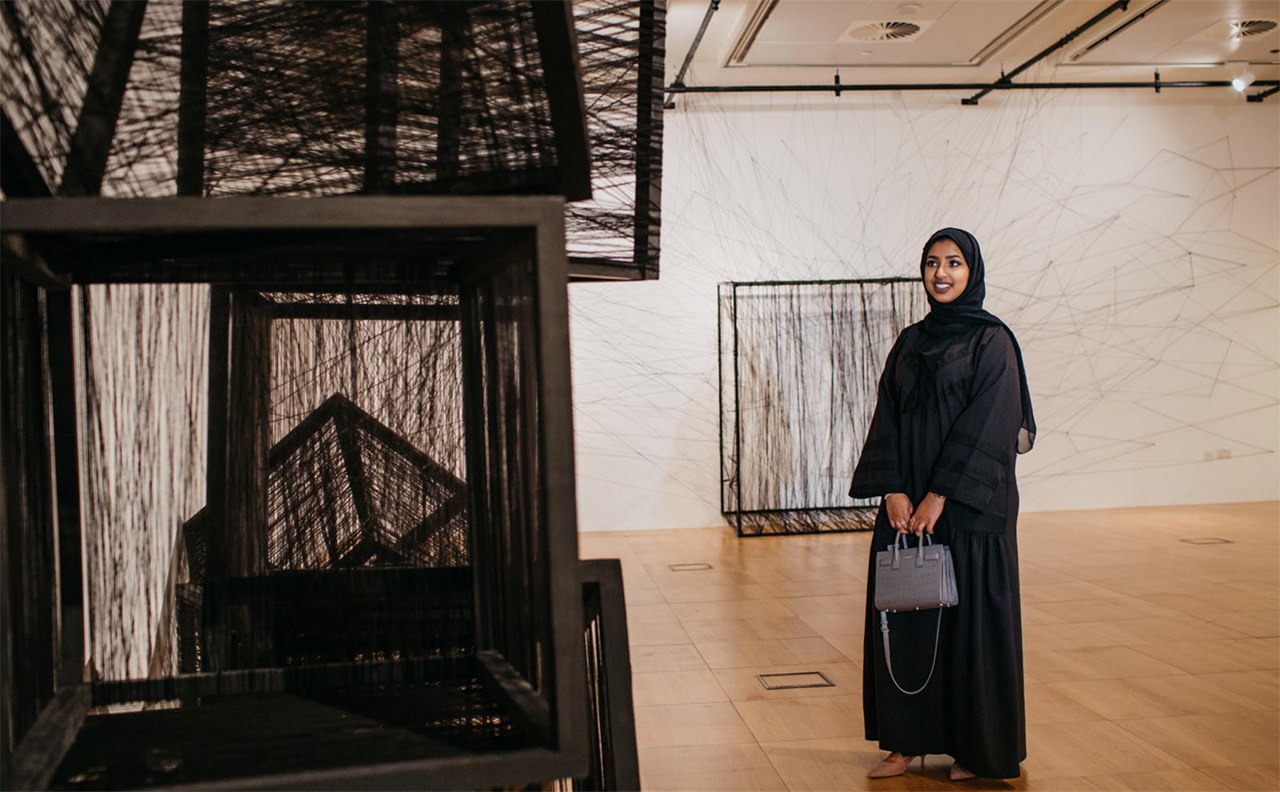 A visitor admiring an installation piece at the NYU Abu Dhabi Art Gallery.
