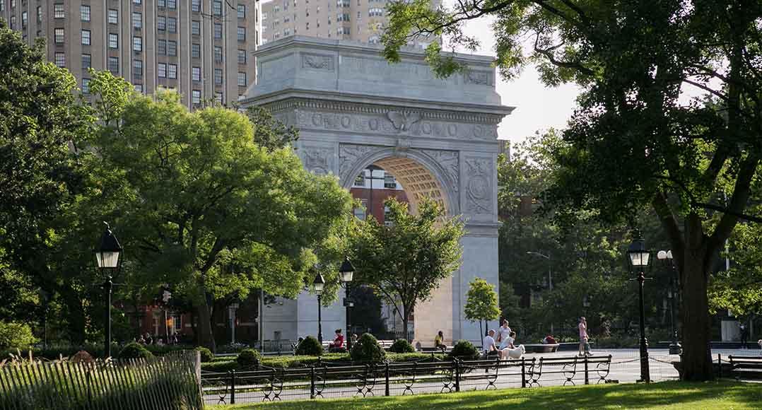 The Washington Square Arch peaks from behind lush green trees