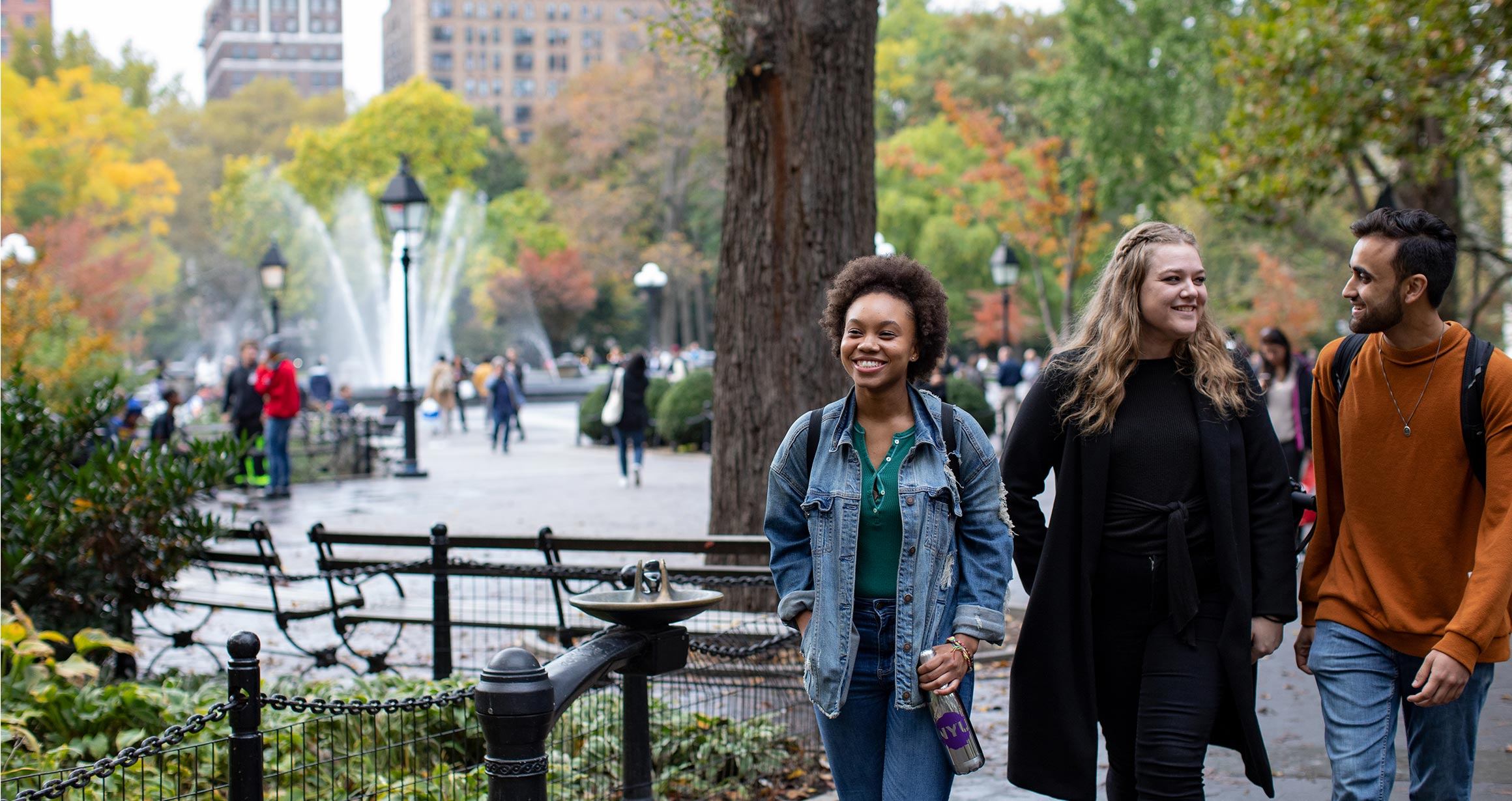 Three students walking through Washington Square Park.