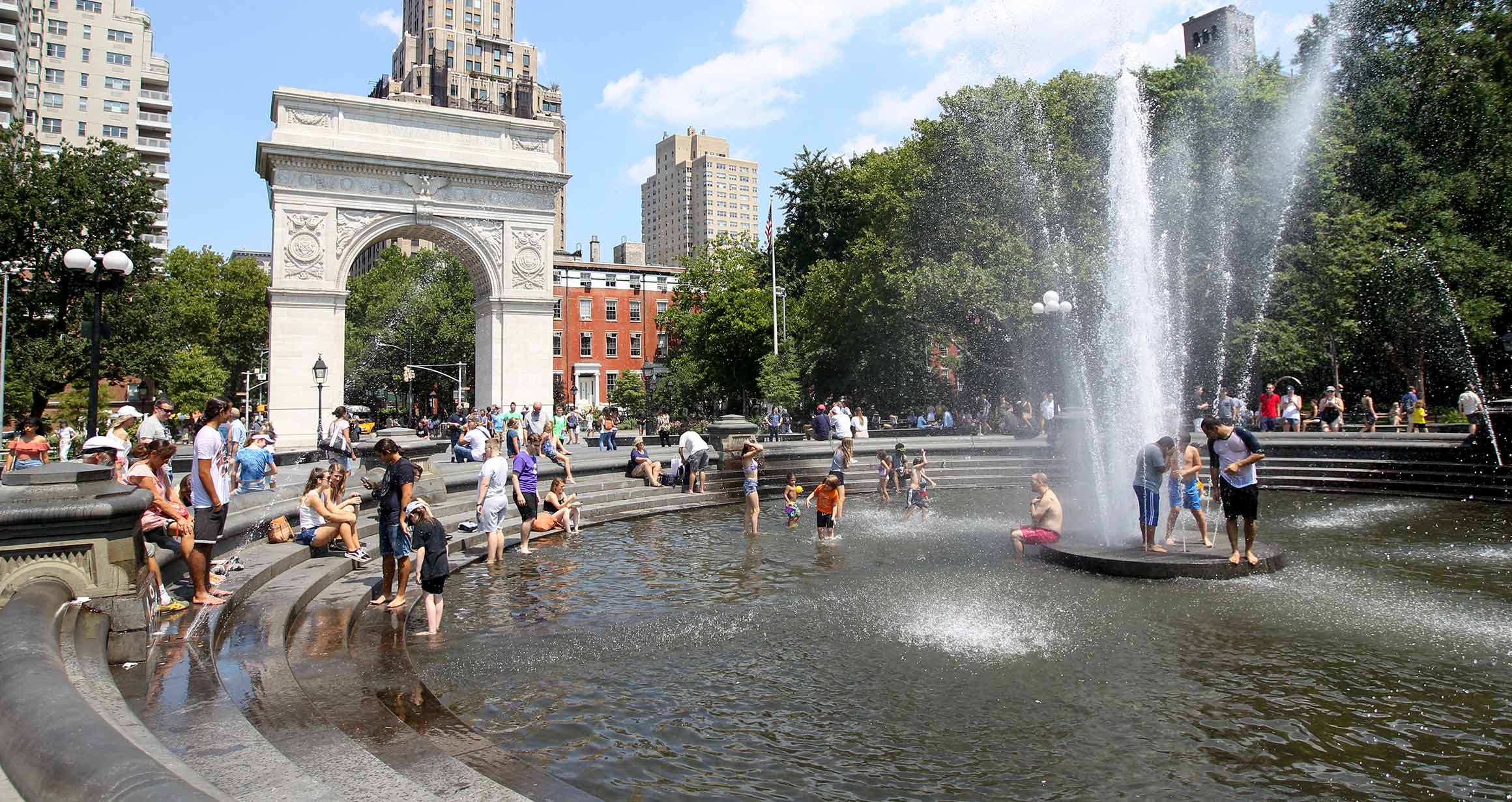 The fountain is Washington Square Park sprays patron as they play in the fountain