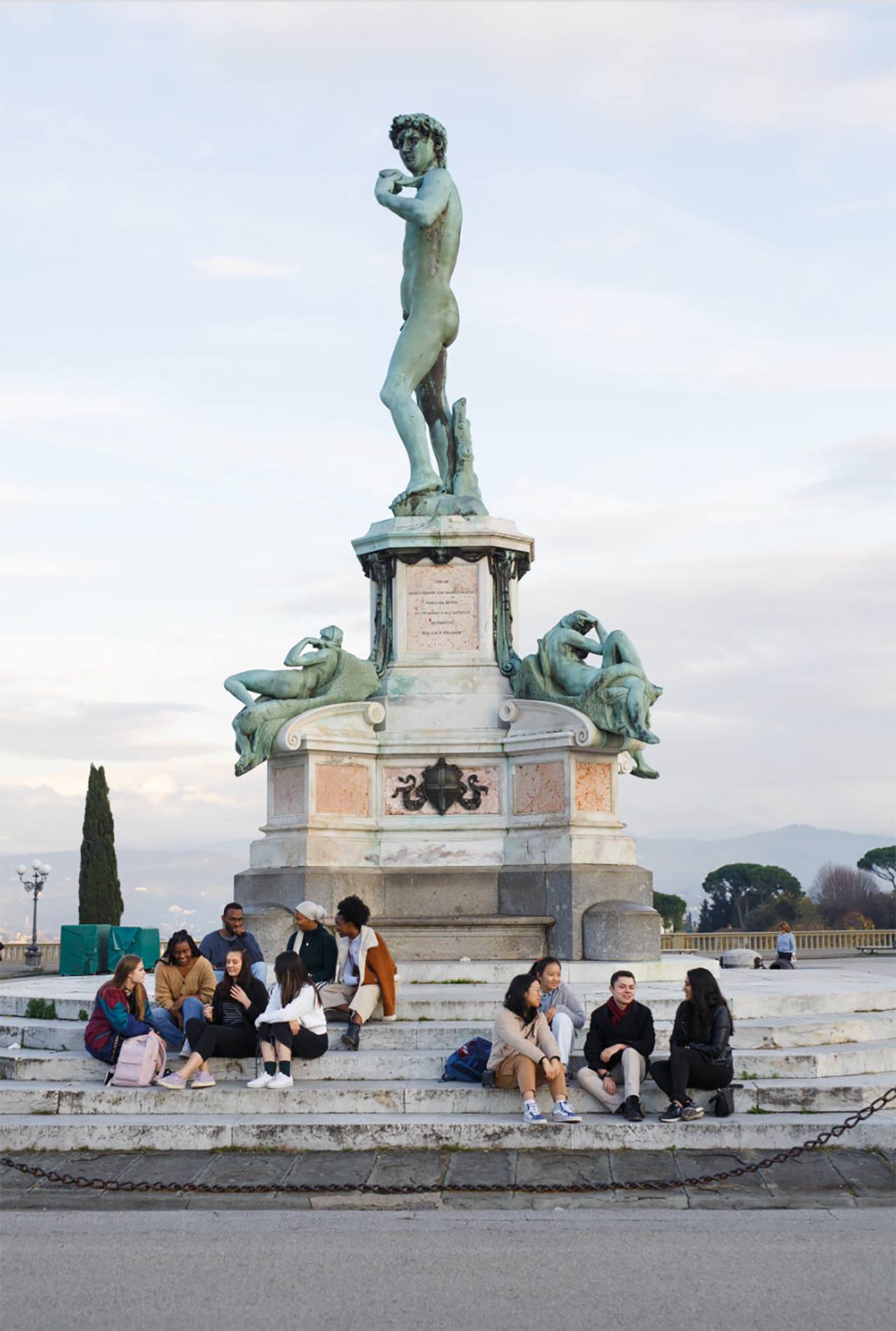 Students hanging out on the steps of a statue in Florence.