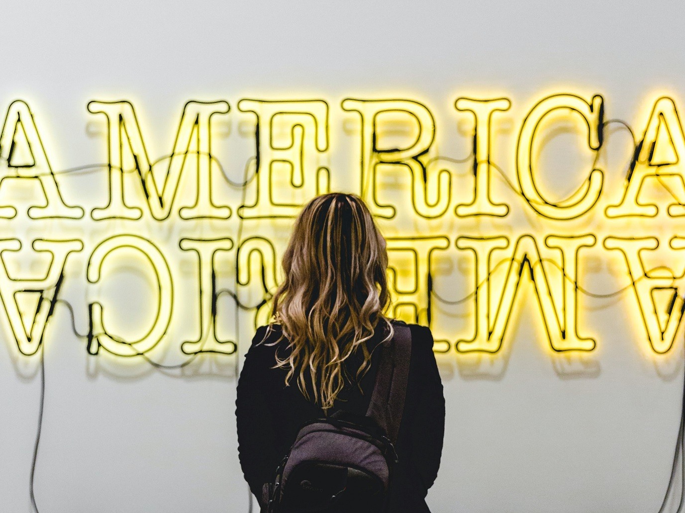 Girl watching America neon sign