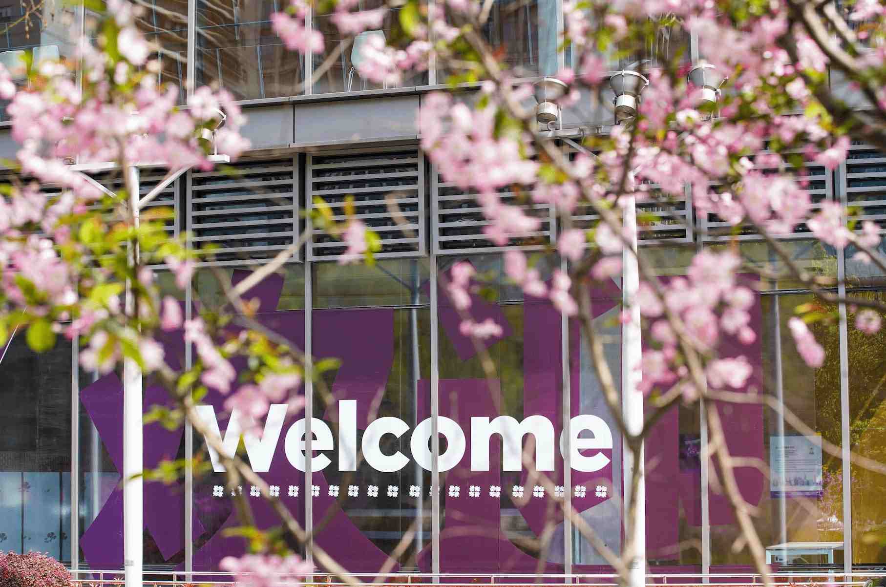 Welcome sign behind a tree of flowers