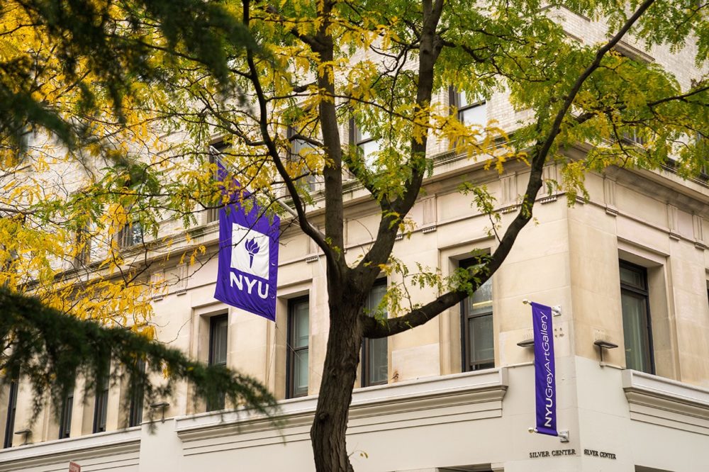 An NYU flag hanging off a campus building.